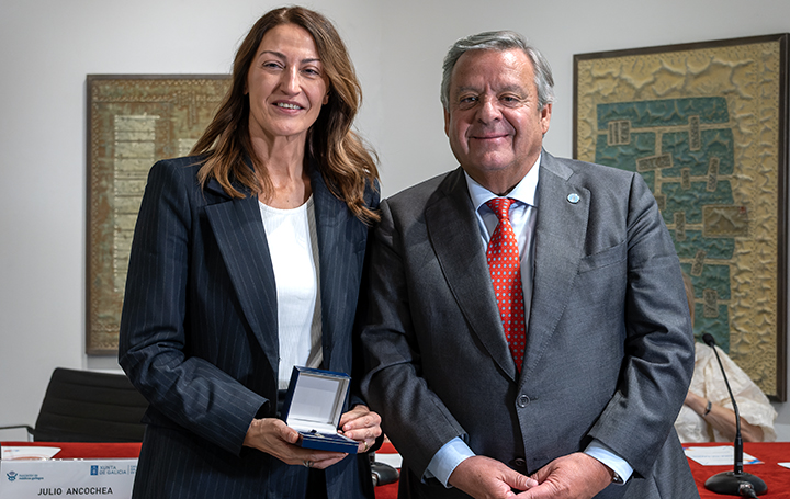 La directora científica del Inibic, Mar Castellanos, posa con la Insignia junto al presidente de Asomega.