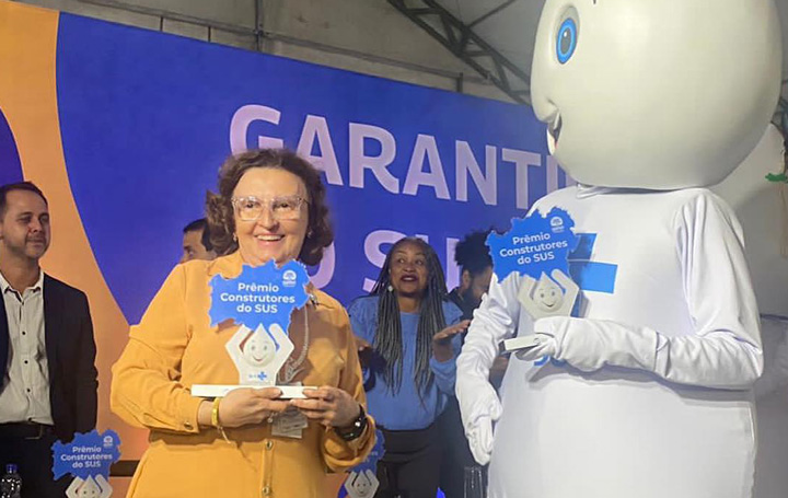 Dolores Fernández recibe su reconocimiento en presencia del popular personaje Gotinha, icono para estimular la inmunización de toda la población.