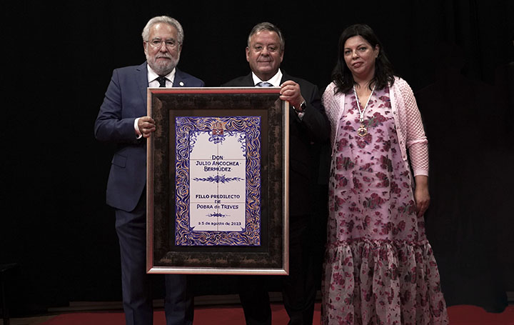 Miguel Santalices, presidente del Parlamento de Galicia, y Patricia Domínguez, alcaldesa de A Pobra de Trives, flanquean a Julio Ancochea tras entregarle un mosaico con su nombramiento como Hijo Predilecto.