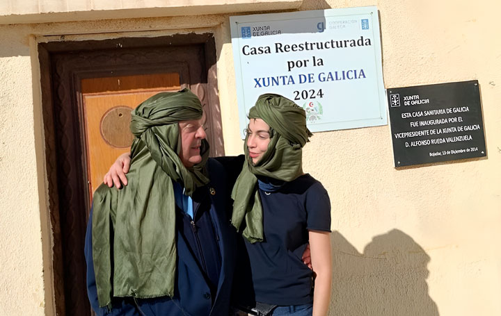 Julio Ancochea y Ruth Campos frente a la Casa de Galicia en Bojador, instalación que, como reza la placa a sus espaldas, "fue inaugurado por el vicepresidente de la Xunta de Galicia D. Alfonso Rueda Valenzuela" el 13 de diciembre de 2014.