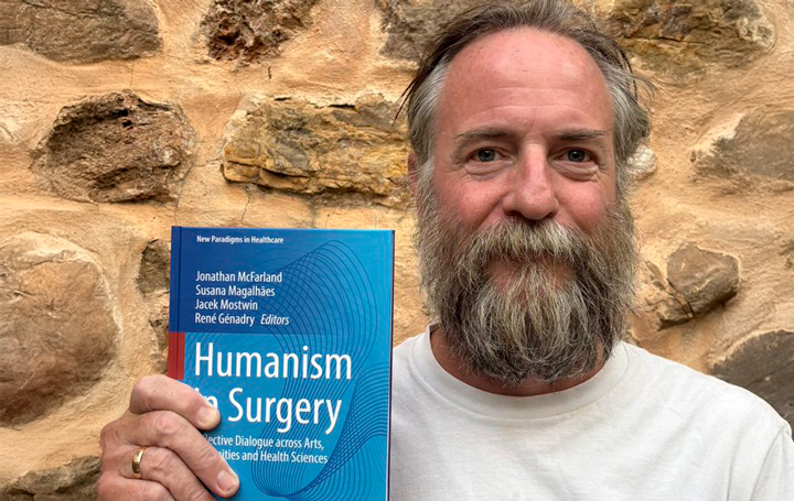 El autor del artículo, Jonathan McFarland, posa con un ejemplar del último libro que ha coordinado, "Humanism in Surgery".